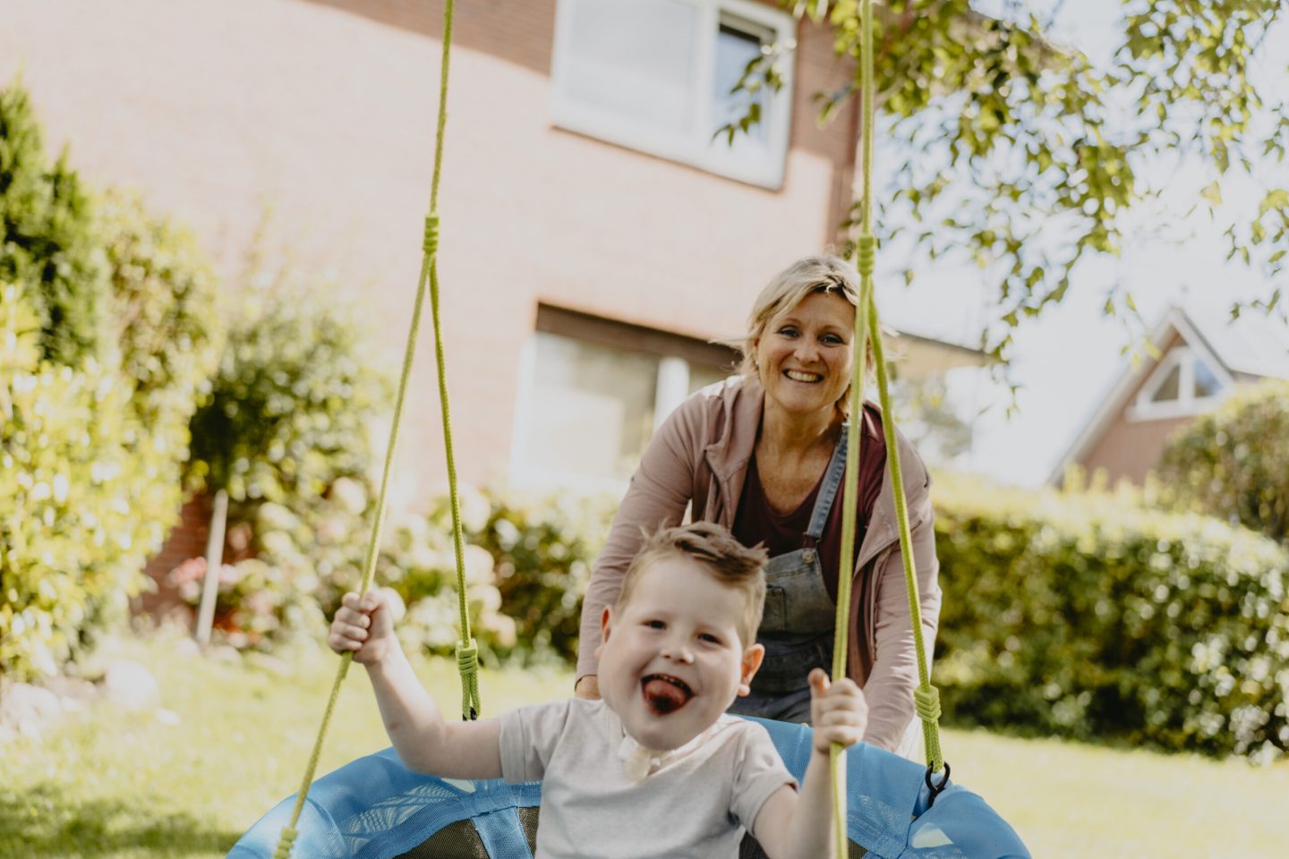 Pflegerin die ein Kind an der Schaukel anschubst