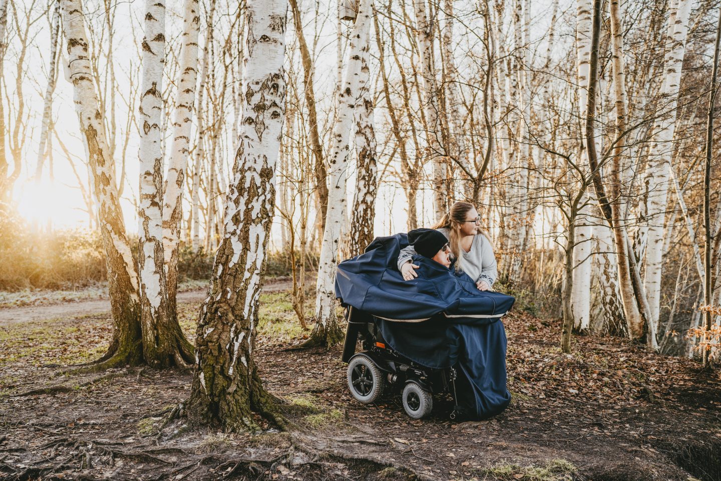 Mitarbeitende gehen mit einem Kunden im Wald spazieren