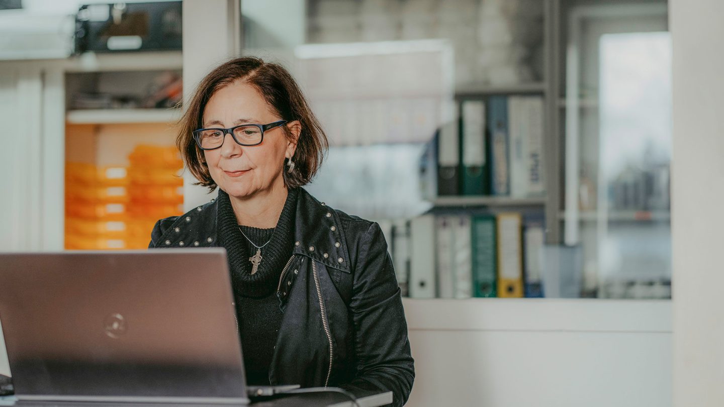 Eine Mitarbeitende sitzt an Ihrem Schreibtisch