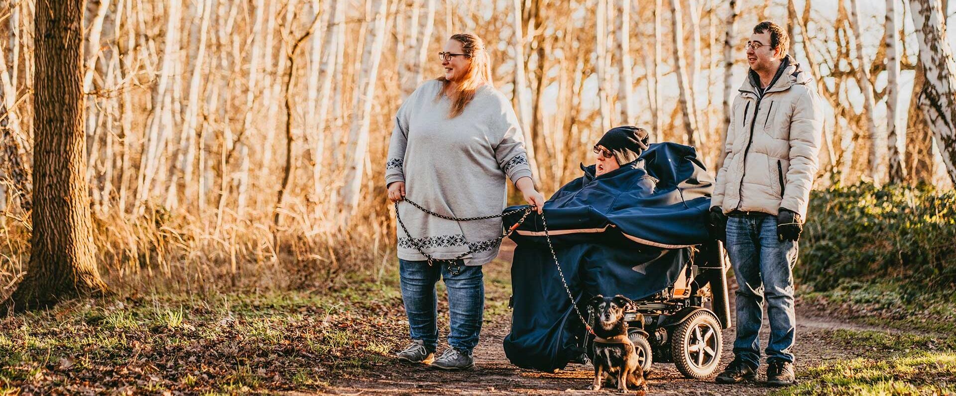 Mitarbeitende des Jona Intensivpflegedienstes gehen mit einem Kunden im Wald spazieren