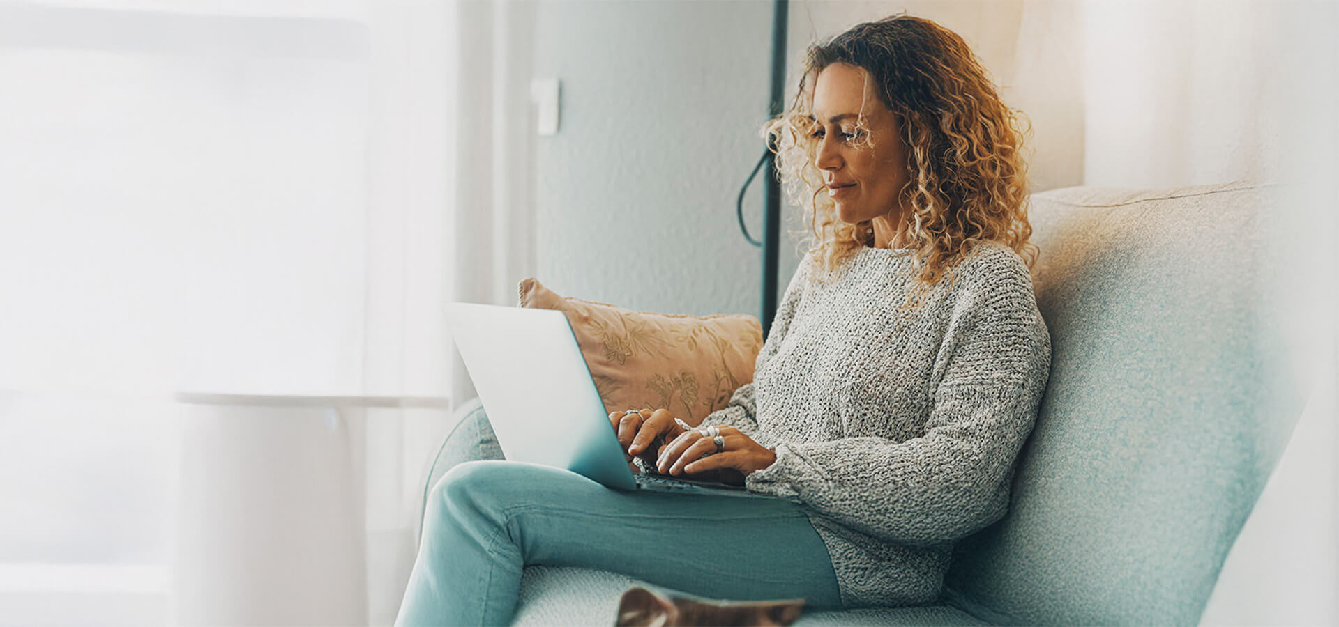 Eine Frau sitzt auf dem Sofa und schaut in einen Laptop